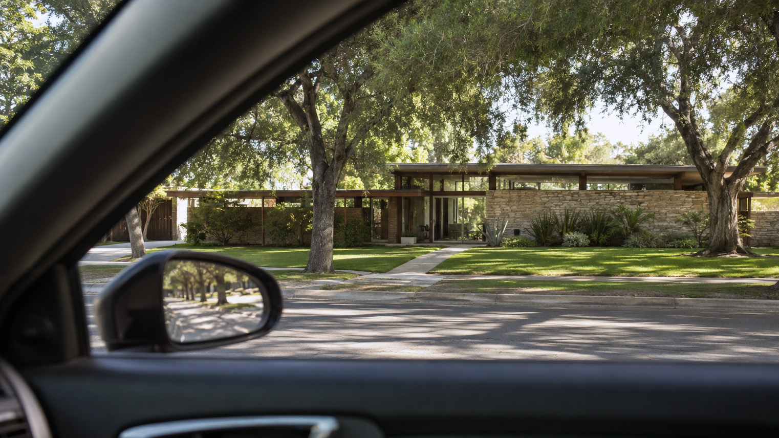 Driver's window view of a mid-century modern home, post and beam with stone wall, behind oaks on a San Gabriel Valley street. AI generated image by Greg Anderson.