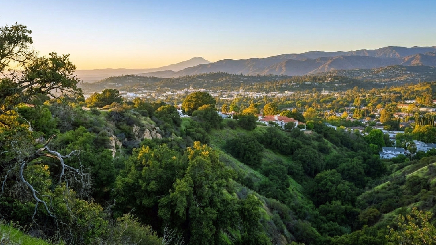 First light panorama from the canyon rim above Sierra Madre, chaparral dropping to the town below, mountains behind.